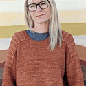 triangular shawl with two stockinette-based charts that create a border of birdhouses at the top straight edge