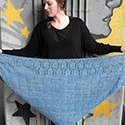 triangular shawl with two stockinette-based charts that create a border of birdhouses at the top straight edge