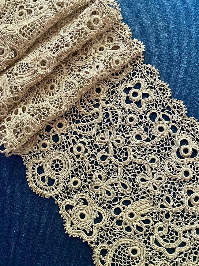 Cream-colored Irish crochet lace with a variet of motifs that look like flowers.